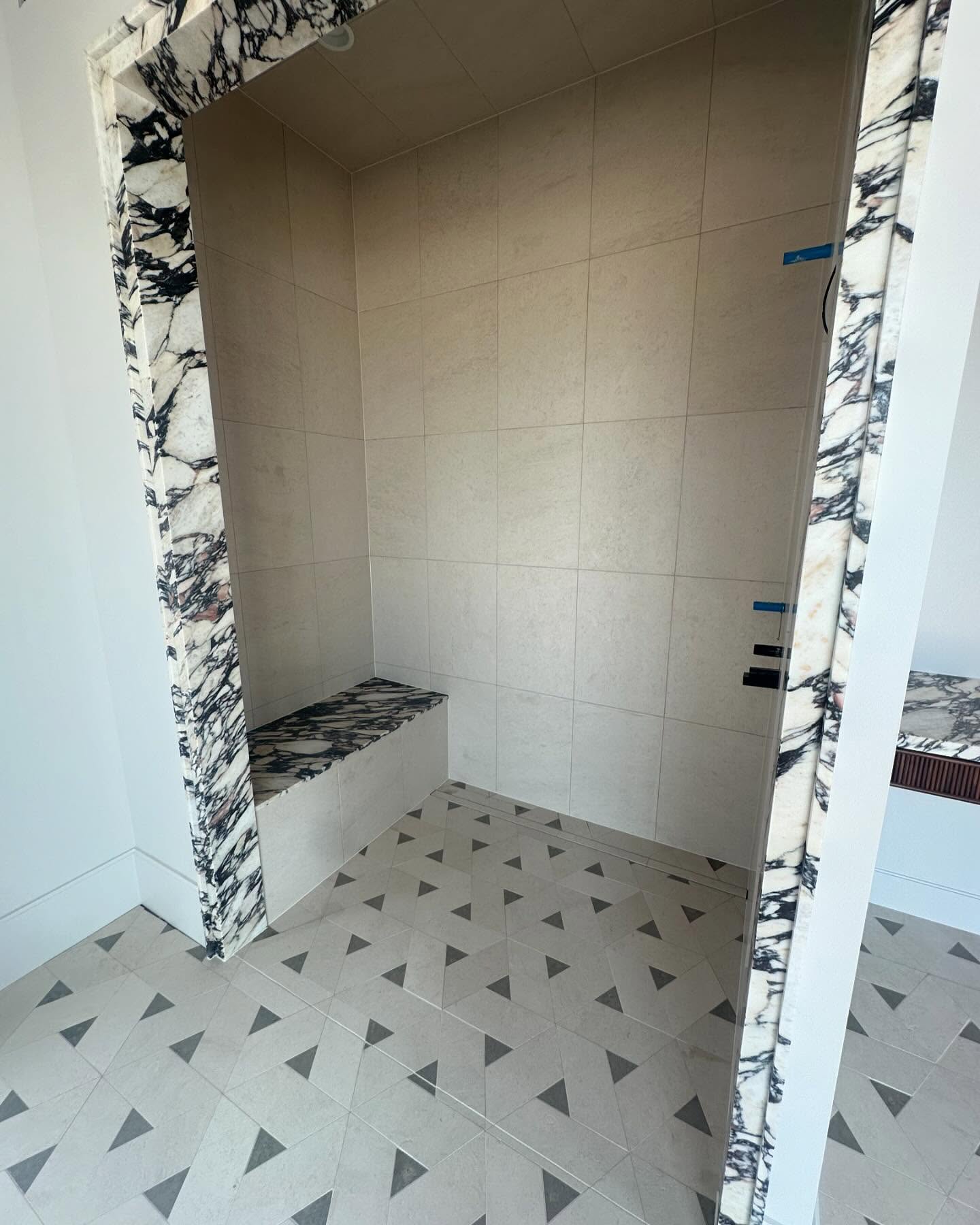 Marble-look custom shower with herringbone floor
